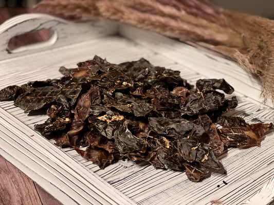 Pile of PupChew dehydrated chicken heart liver and gizzard dog treats on a white wooden tray