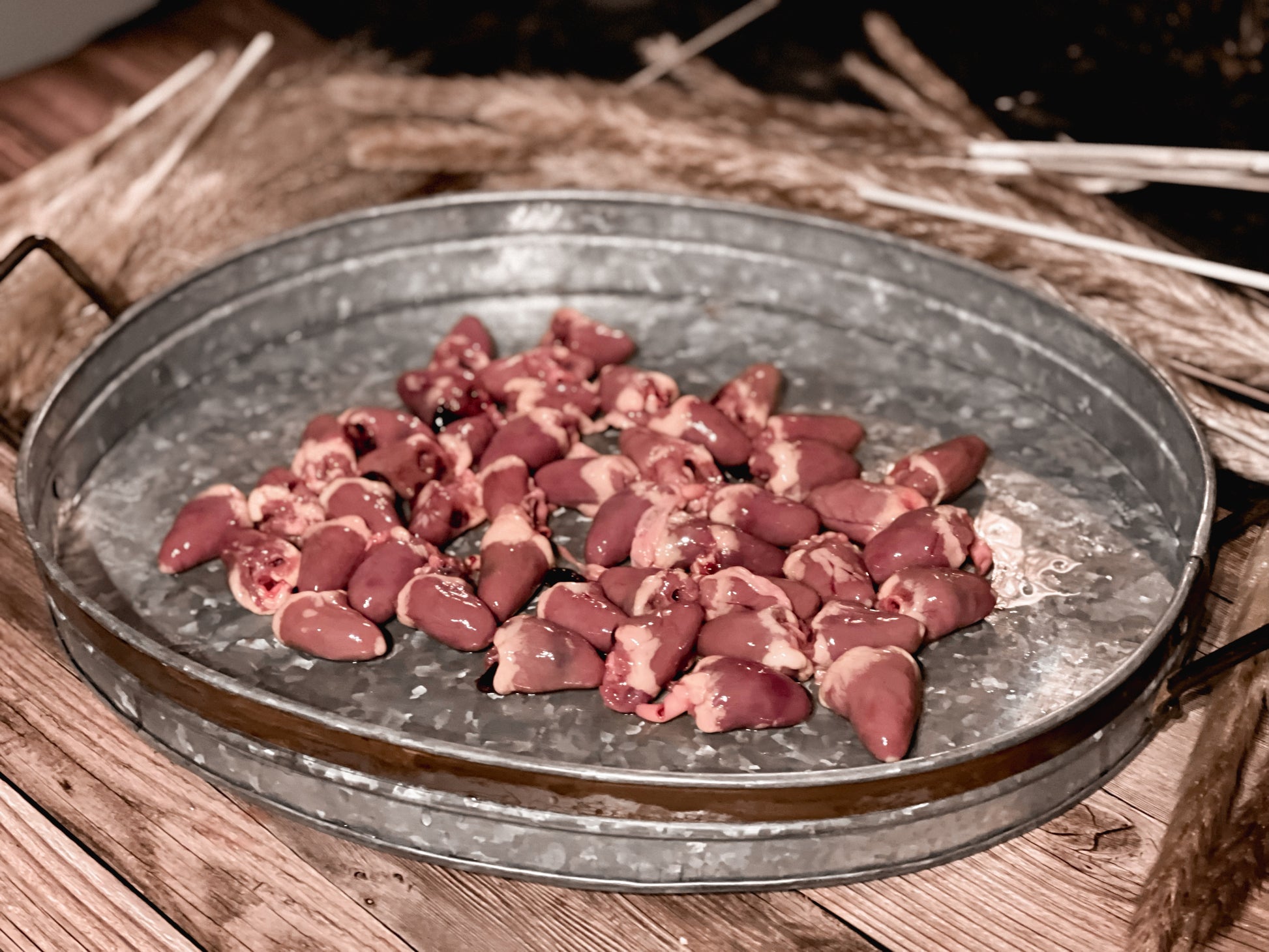 Raw chicken hearts in a galvanized metal tray before dehydration