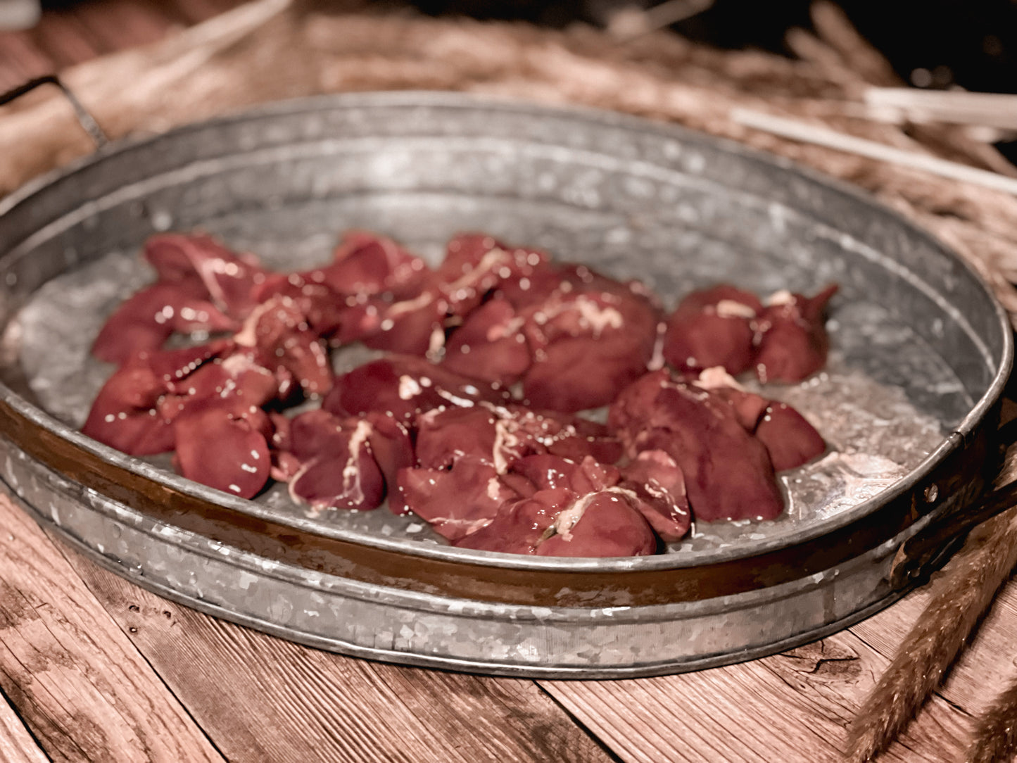 Raw chicken liver pieces in a galvanized metal tray before dehydration