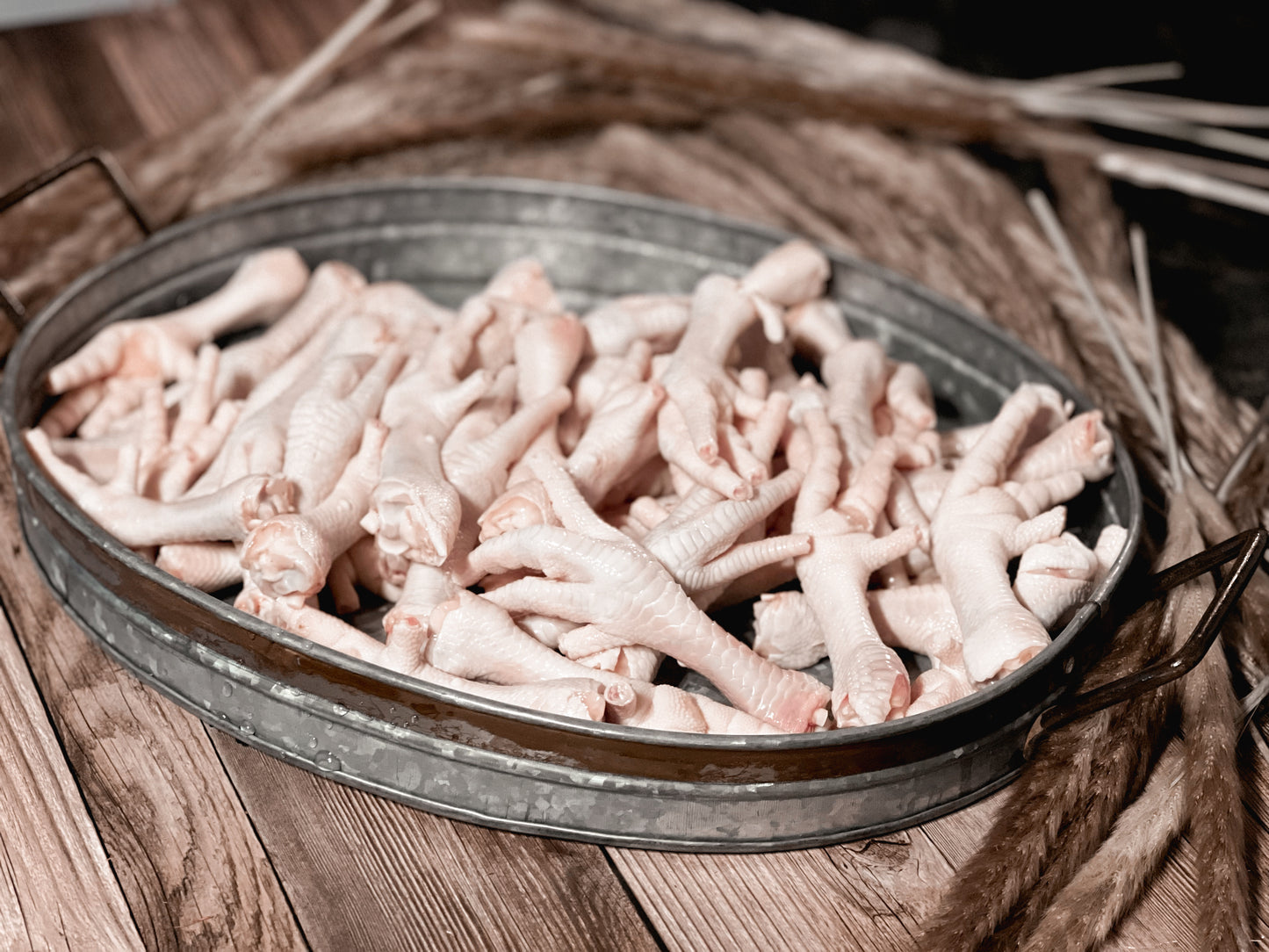 Raw chicken feet in a galvanized metal tray before dehydration