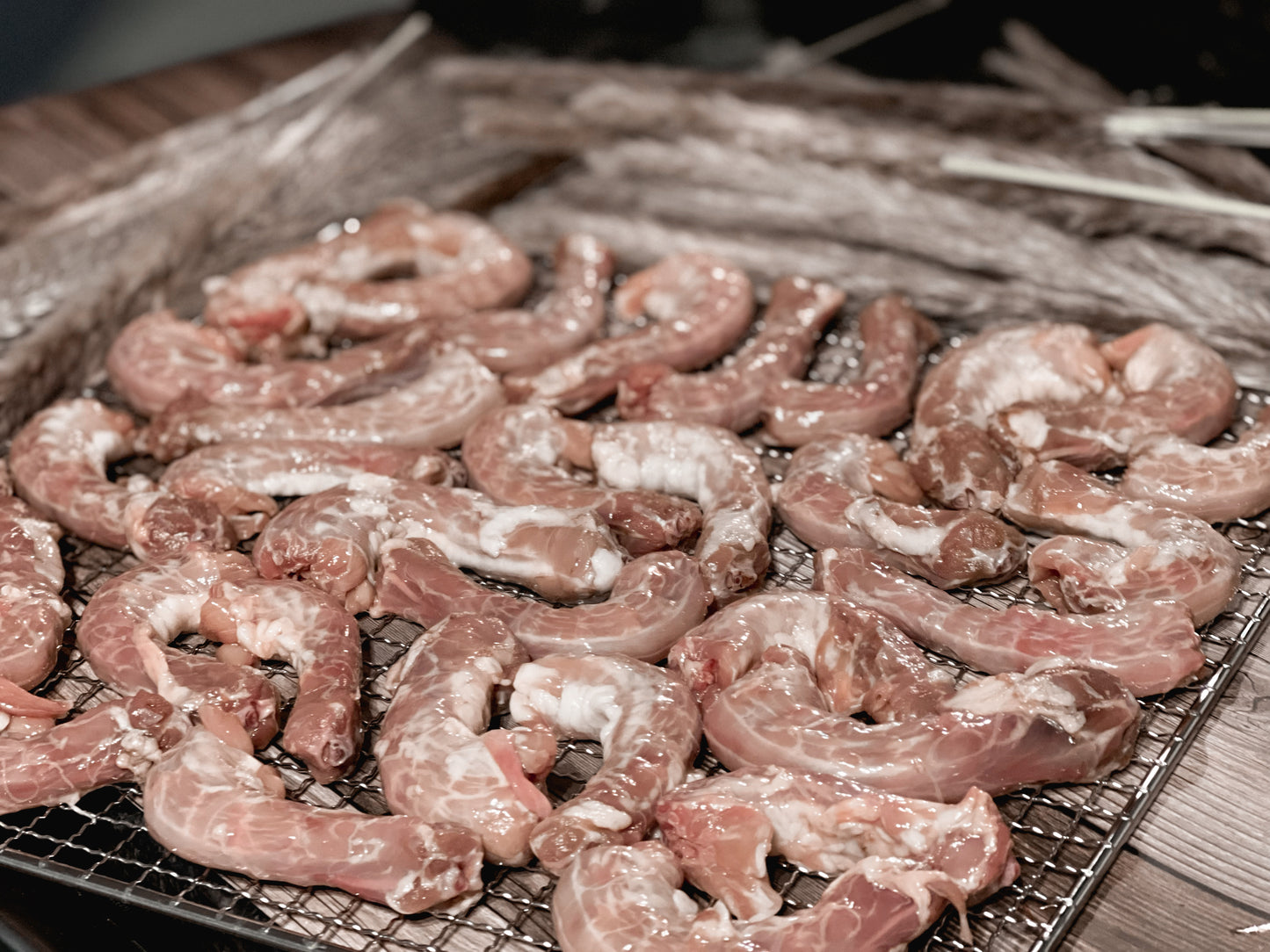 Raw chicken necks arranged on a mesh dehydrator rack